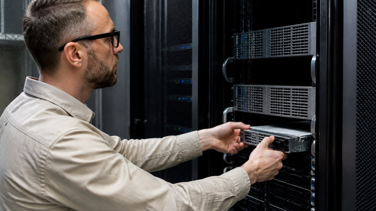 Database administrator working at desktop with multiple monitors displaying SQL Server Management Studio and automated cloning processes in progress with real-time status dashboards