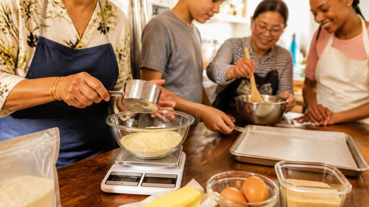 Diverse group of home bakers preparing almond flour, butter, and eggs on a kitchen counter for a baking session
