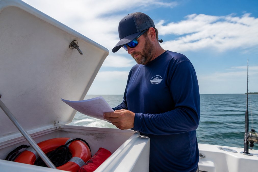 Visual roadmap for Professional fishing guide standing on the deck of a charter boat, checking safety equipment and ...