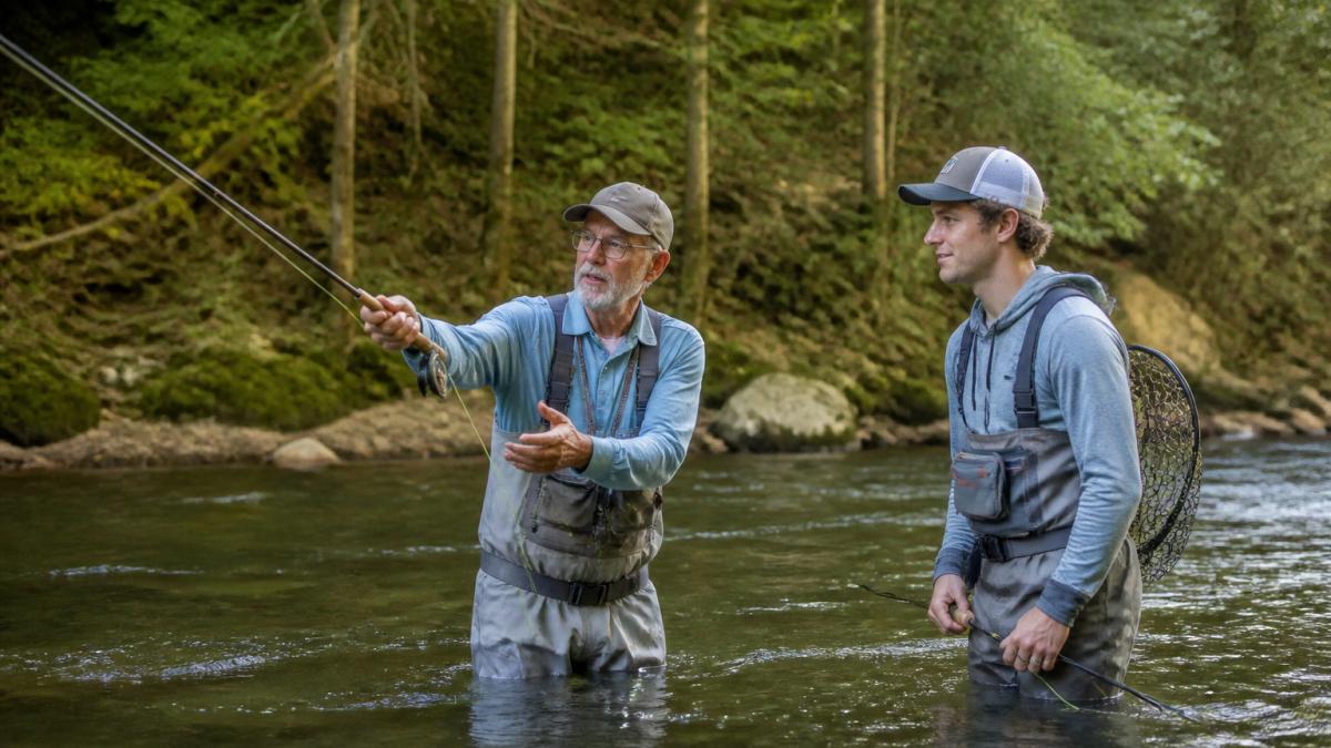 Fly fishing guide demonstrating casting technique to an angler in a river as you prepare to book a fly fishing guide.