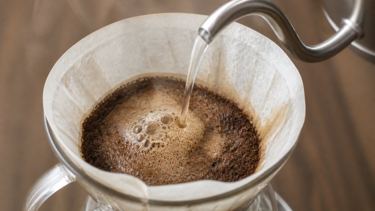 Diagram illustrating the bloom phase process of pouring hot water over coffee grounds using a gooseneck kettle.