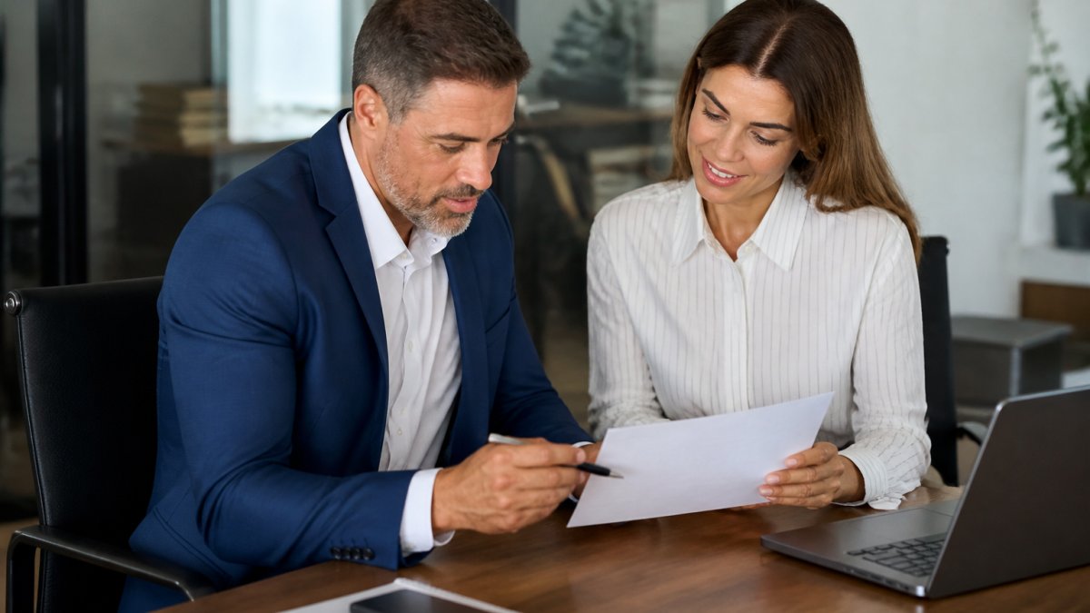Sales manager and prospect reviewing a printed lead qualification checklist at a bright office desk