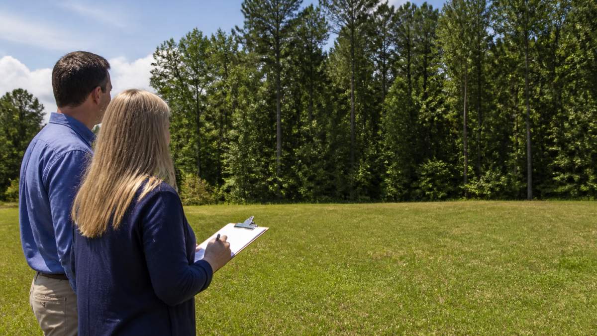 A couple reviews plans on a grassy lot for their custom home in Georgia
