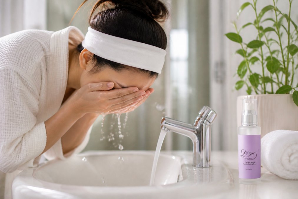 Person gently cleansing their face with a soft cleanser and lukewarm water, hands cupping face over a bathroom sink with soft natural lighting