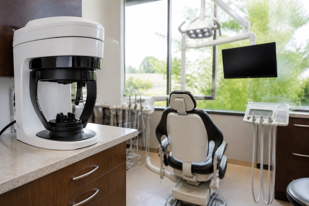 Modern dental operatory with 3D imaging equipment, digital displays, advanced restorative technology, and chairside monitors in a bright, clean clinical setting with natural lighting