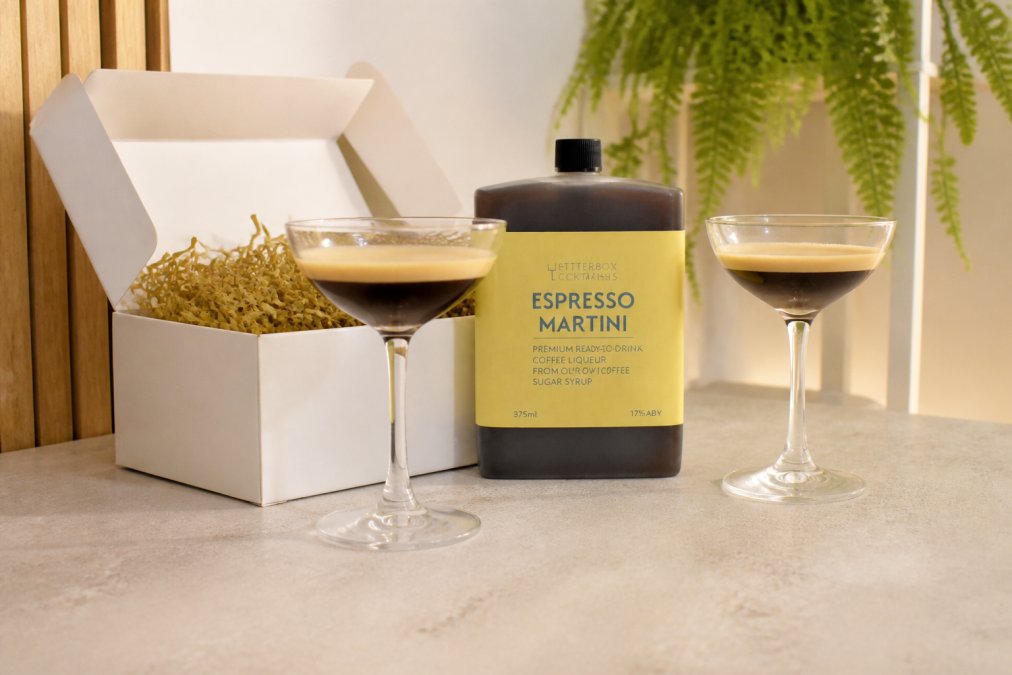 Luxury gift boxes with premium cocktail bottles and elegant glasses displayed on a neutral surface, showing elegant presentation and premium packaging