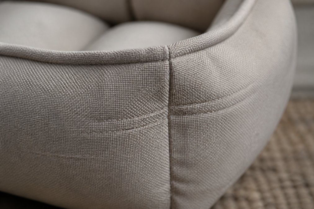 Close-up of high-quality fabric seams and dense stitching on cat bed upholstery, showing reinforced corner construction and tight thread patterns on neutral-colored material