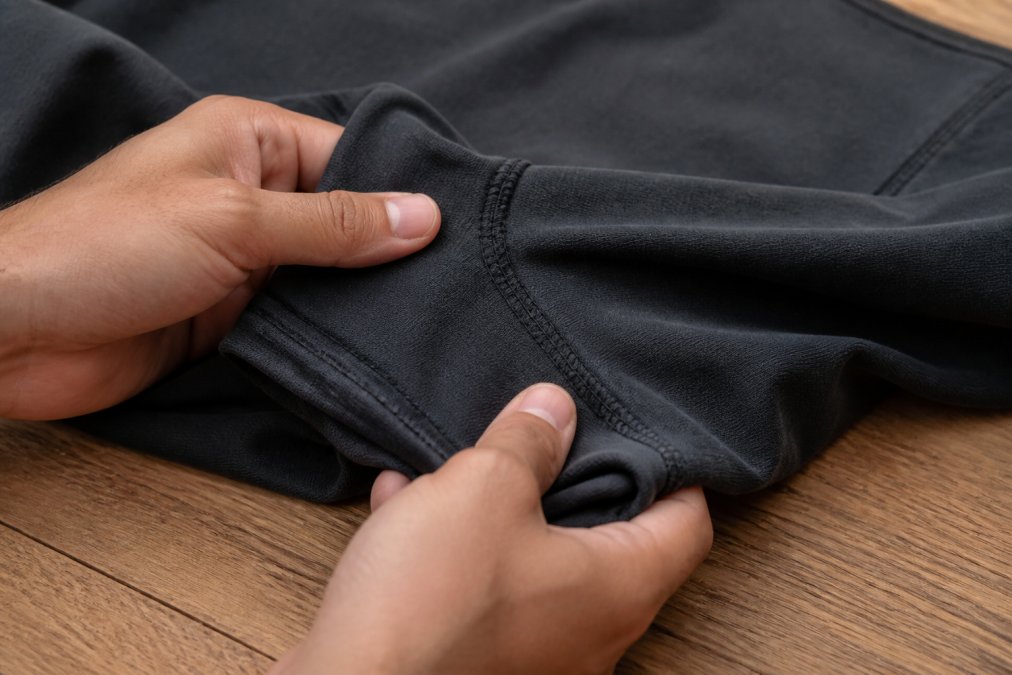 Diagram showing how flatlock stitching and reinforced seams identify durable gymwear during a quality inspection.