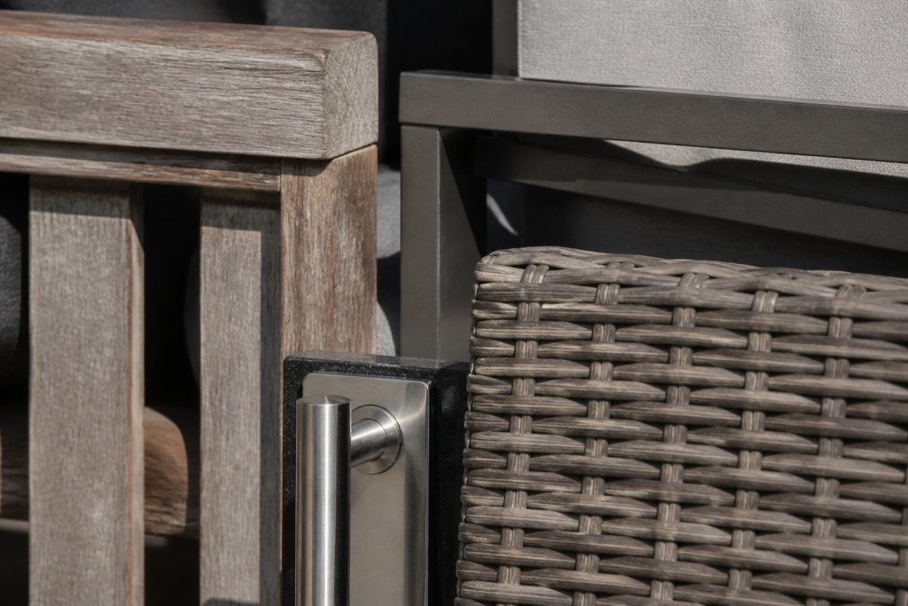 Close-up of various outdoor furniture materials displayed in natural sunlight, teak wood grain, powder-coated aluminum frame detail, synthetic wicker weave, and stainless steel hardware, showing texture and weathered patina on wood surfaces