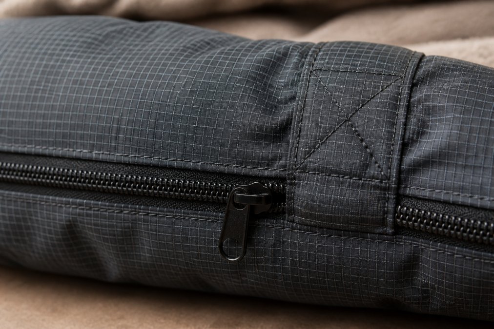 Close-up of ripstop fabric texture showing reinforced crosshatch weave pattern with heavy-duty zipper and visible stitching reinforcement on a durable pet bed