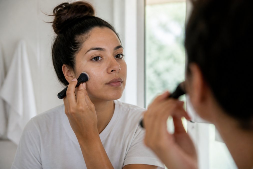Buffing foundation onto a cheek with a dense kabuki brush to learn how to choose foundation for textured skin