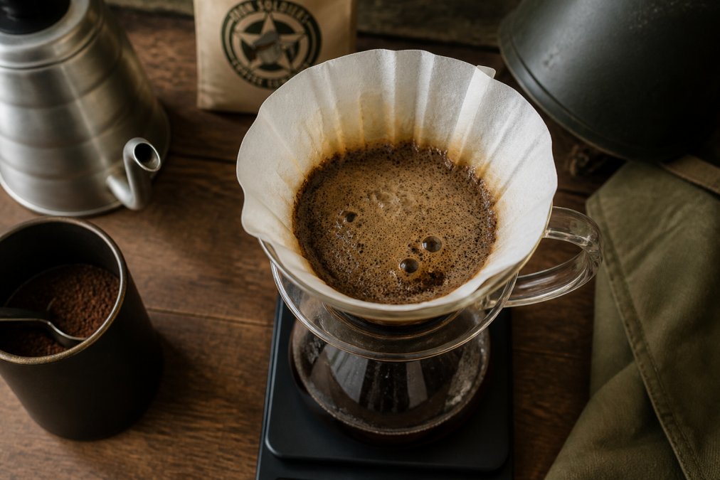 Bubbling bloom phase during a pour-over brew of fresh roasted coffee on a wooden kitchen counter