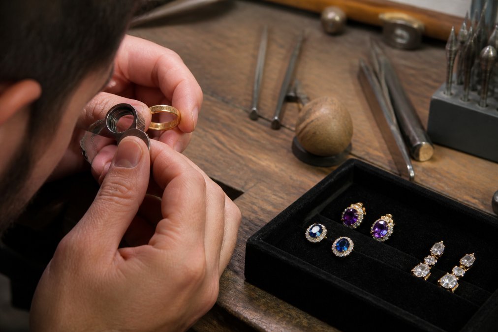 Jeweler using a loupe to inspect the hallmark on an heirloom quality jewelry gold ring