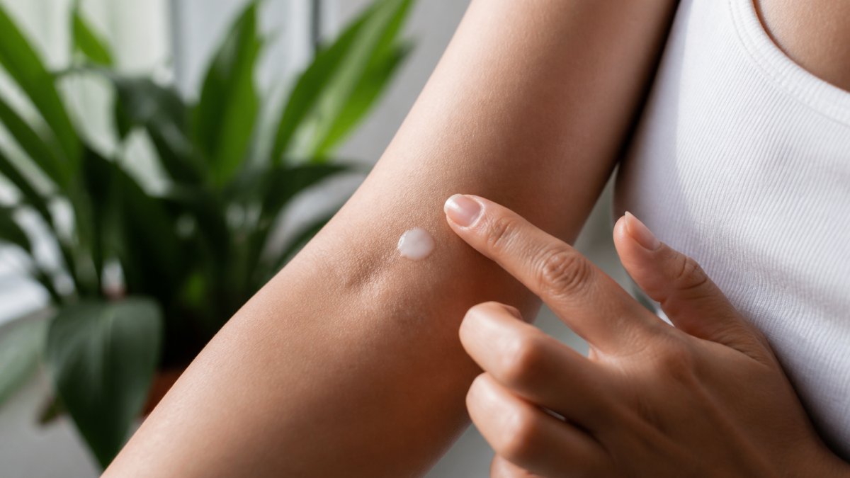Close-up of a person's arm showing proper patch test application of a small amount of moisturizer on clean skin, with natural daylight illuminating the test area