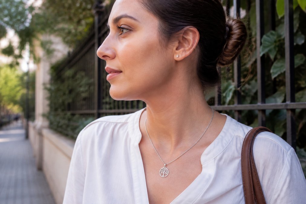 Person wearing a personalized necklace in white gold, shown from the side in natural daylight, highlighting how the metal appears against skin tone and demonstrating comfortable all-day wear during typical daily activities