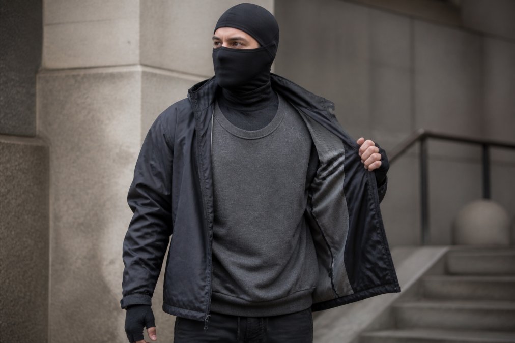Person wearing a complete layering system with fitted base layer, oversized heavyweight sweatshirt mid-layer, and water-resistant jacket, standing outdoors in natural light demonstrating how each layer moves independently