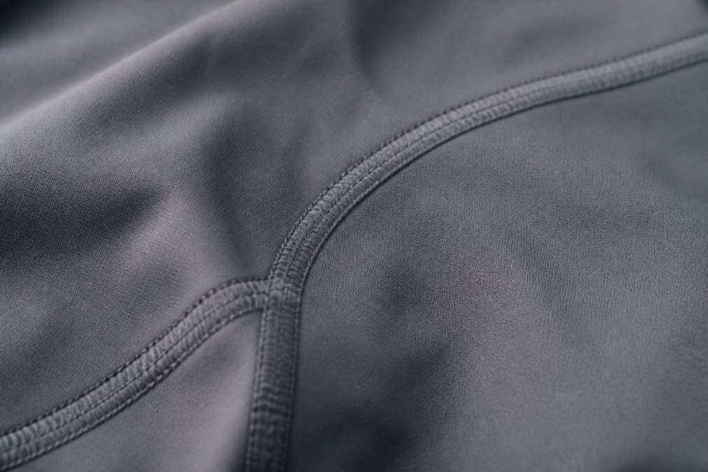 Close-up of seamless flatlock seams on a performance shirt showing the smooth construction detail where fabric edges are stitched flat against each other, demonstrating professional-grade seam quality
