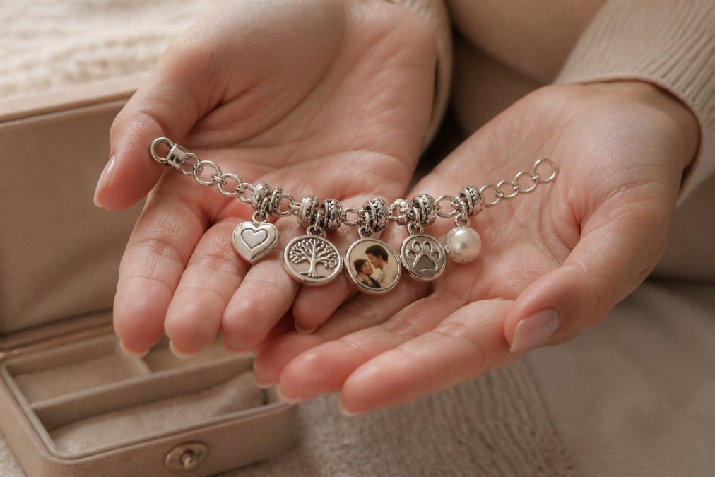 Close-up of hands holding a personalized engraved charm bracelet with custom charms and dates, soft natural lighting highlighting the craftsmanship and individual charm details
