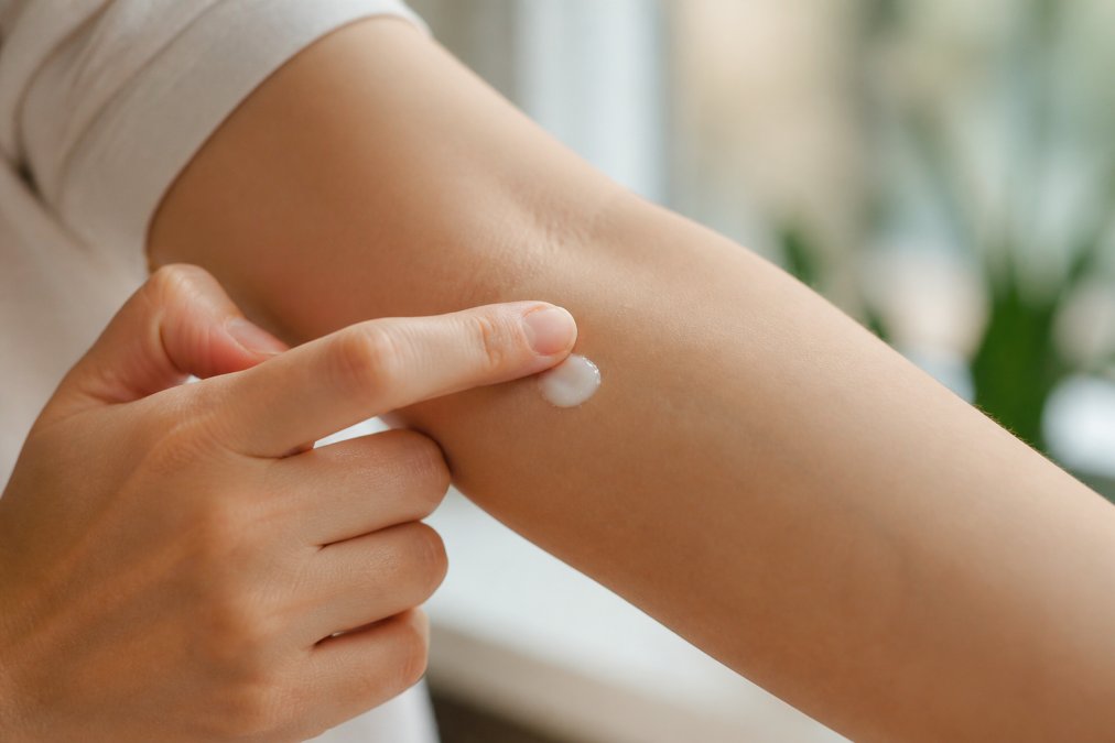Close-up of a person's inner arm with a small amount of product being gently applied with a fingertip, showing careful patch testing technique with soft natural lighting