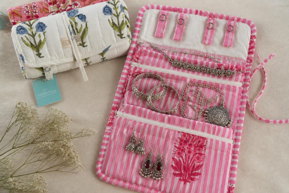 A neatly organised jewellery roll and pouch displaying various silver bracelets, necklaces and earrings stored safely in soft cotton fabric with anti-tarnish protection