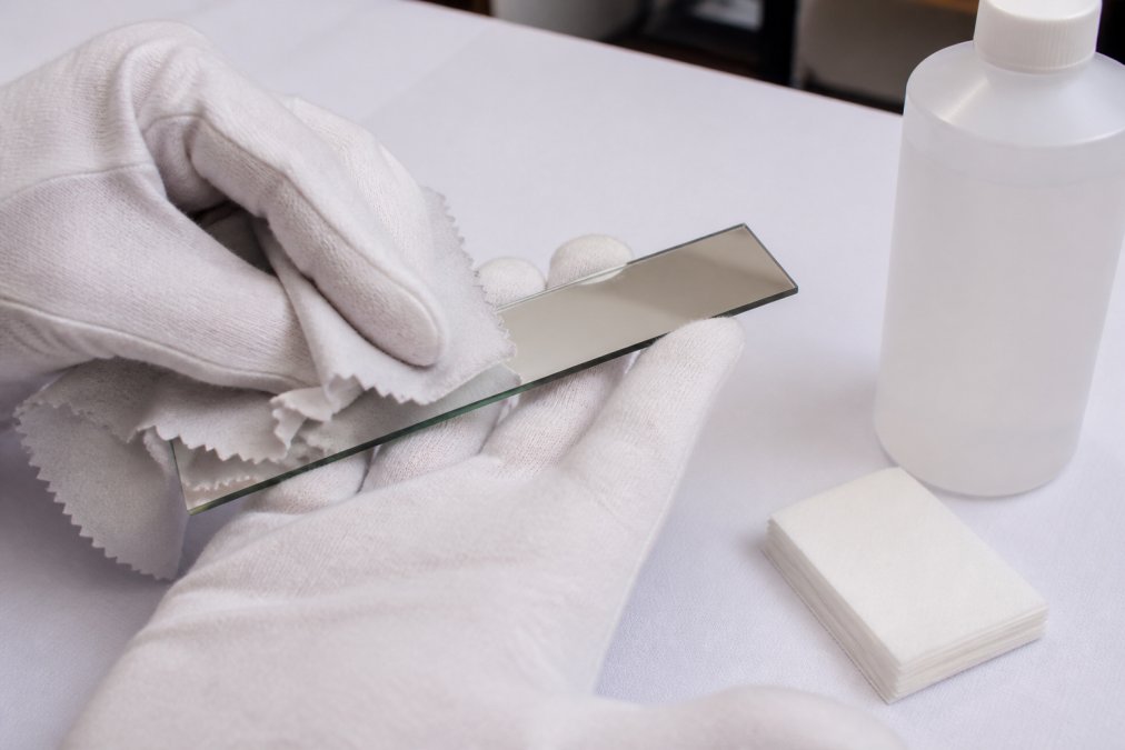 Step-by-step guide on how to clean kaleidoscope mirror systems using cotton gloves and lens tissue.
