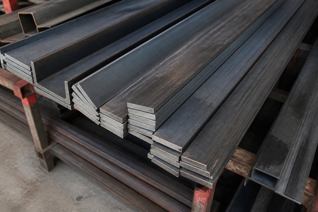 Stack of hot-rolled carbon steel bars showing blue-gray mill scale finish on warehouse racks