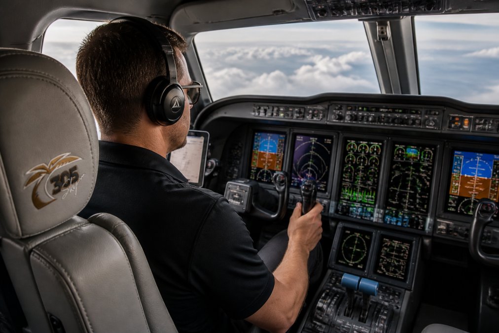 Cockpit interior during flight test showing pilot monitoring multiple avionics displays and engine instruments, with focus on data collection and system monitoring in natural cockpit lighting