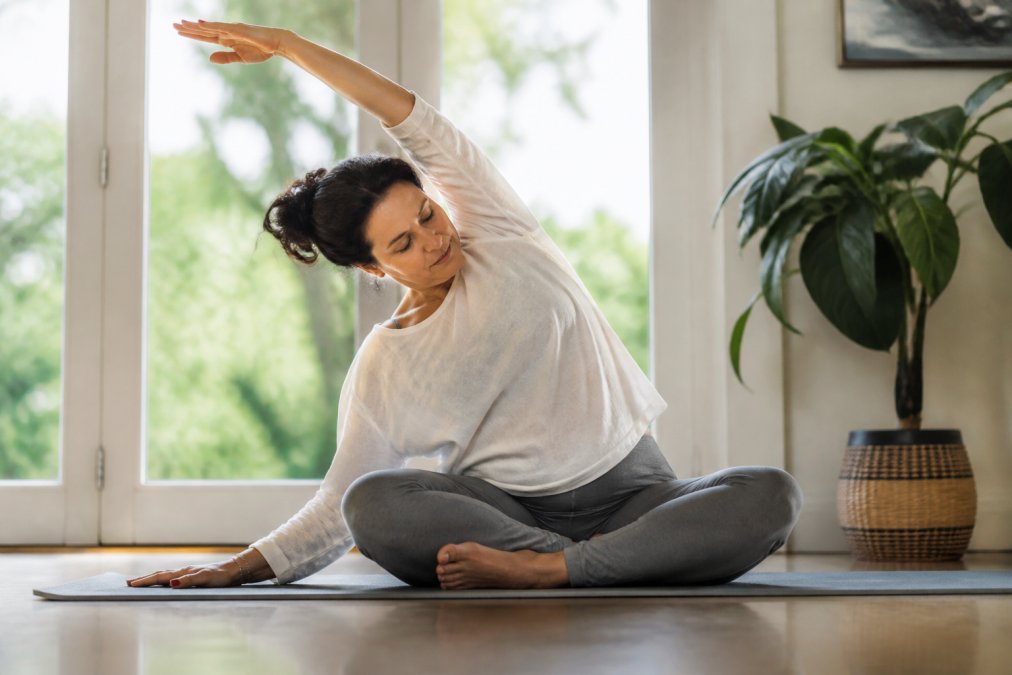Person performing mindful, gentle stretches at home to cope with unbearable pain through controlled movement.