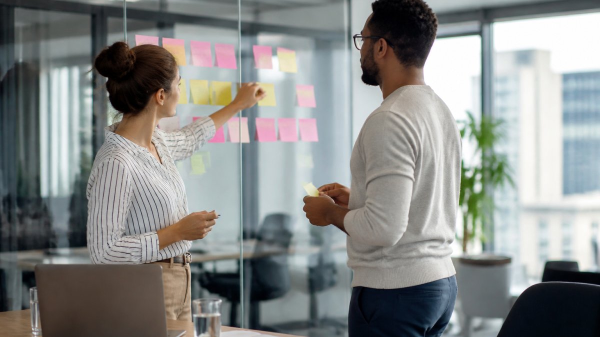 Learning designer and expert mapping a bite-sized learning storyboard on sticky notes in a modern office.