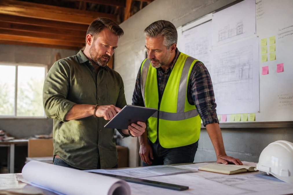 Business owner and manager reviewing a project checklist to delegate business tasks in a construction office.