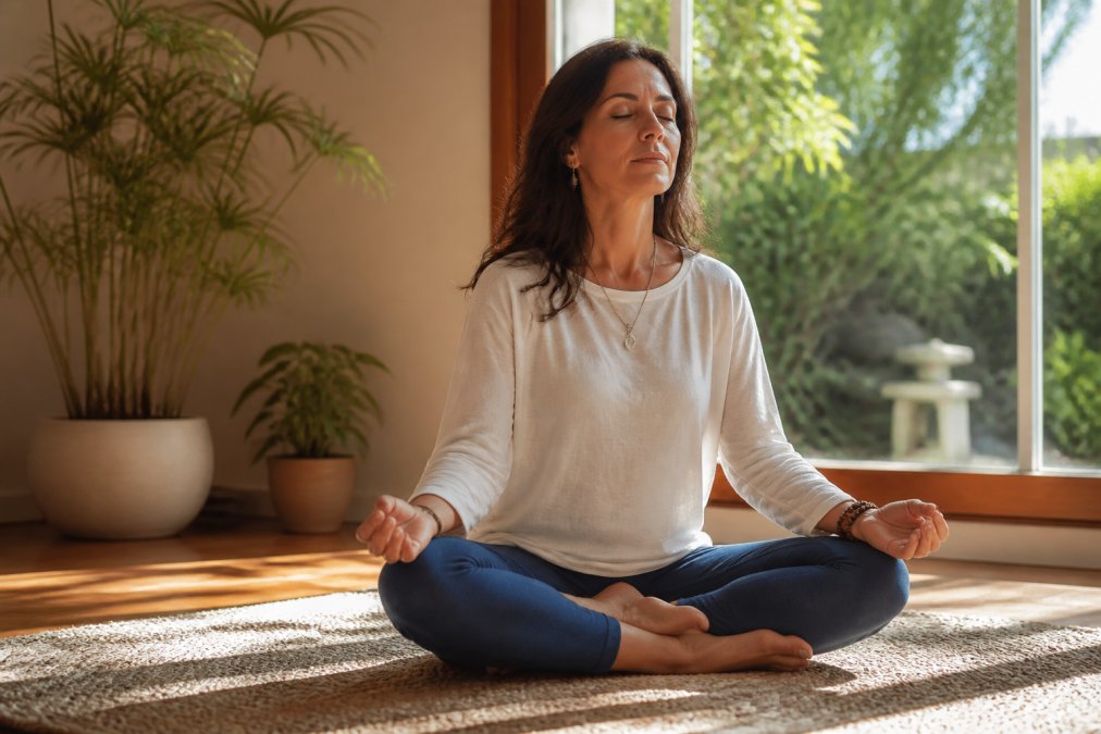 How to Develop Psychic Awareness Naturally 1 A woman sitting peacefully in a sunlit room, eyes closed in meditation, hands resting softly on her knees with a calm expression