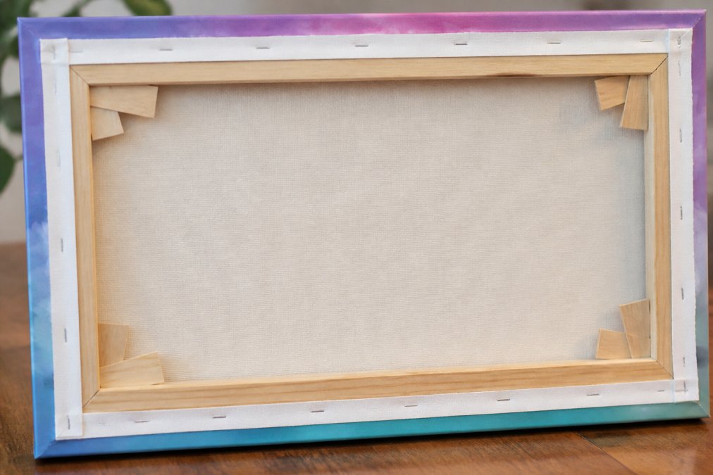 Detailed view of the back of a stretched canvas print showing corner wedges inserted into slots, kiln-dried wood stretcher bars with clean joints, and evenly tensioned canvas with no visible slack or wrinkles