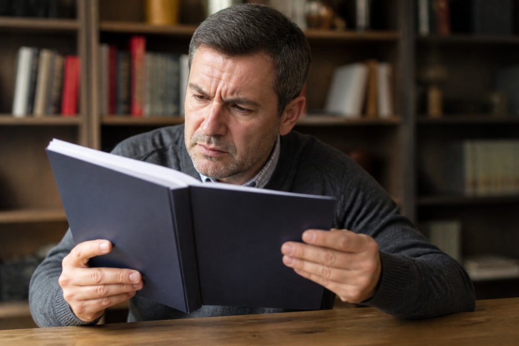 Close-up of skeptical reader examining book or document with critical expression, hands holding pages, suggesting careful evaluation of written content