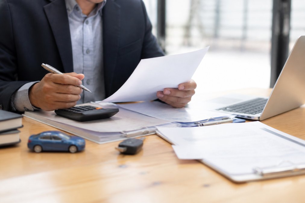 Professional reviewing loan documents and a calculator to finance car no credit options at a desk.
