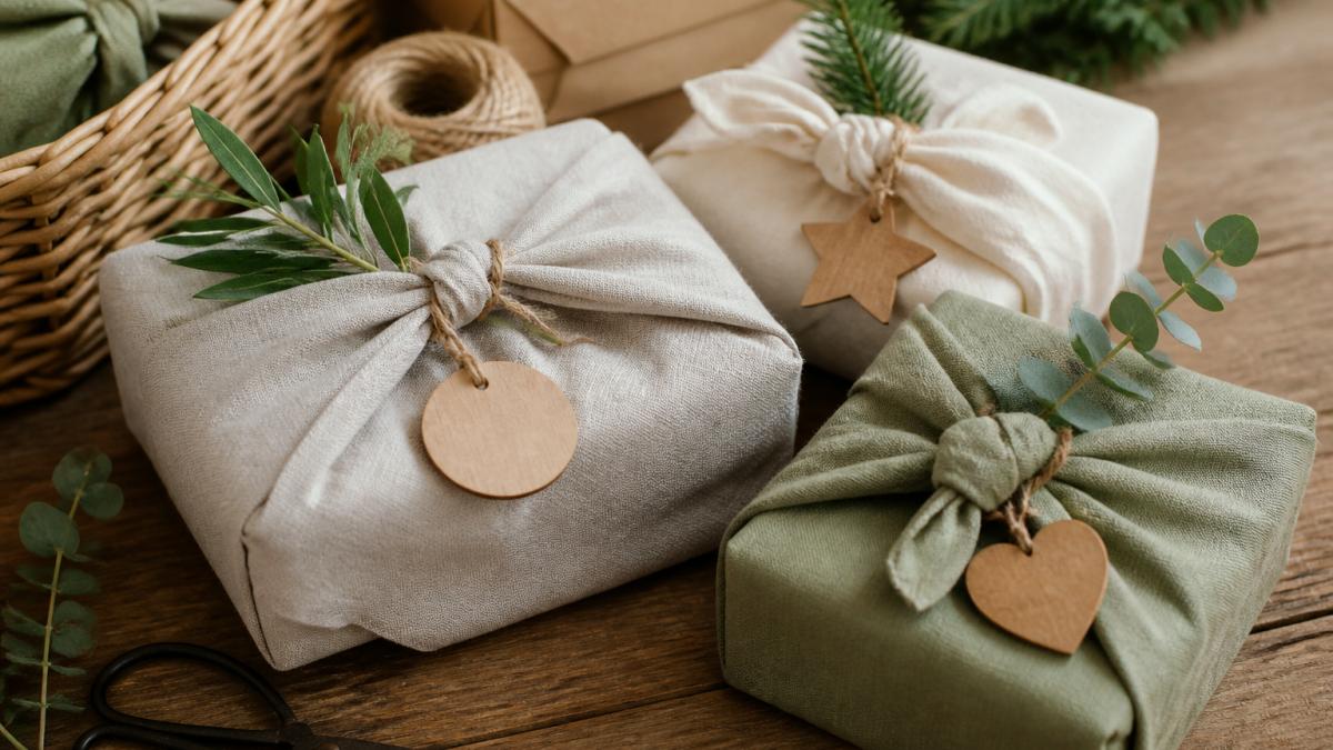 Close-up of beautifully wrapped ethical gifts on a wooden surface with natural materials like fabric wrapping, wooden tags, and sustainable packaging