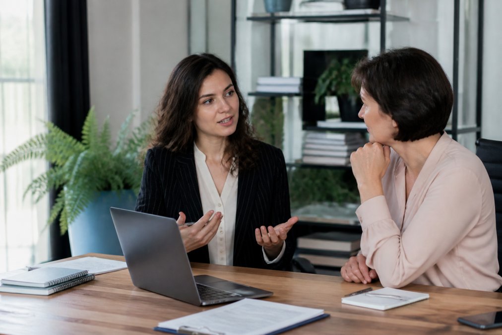 Woman in business attire discussing professional leadership development sponsorship with her manager in an office