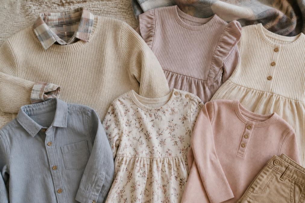 Close-up flat lay showing coordinated pieces: cream-toned sweater with plaid accents, matching coordinated tops in soft pastels, and how individual pieces work together in a cohesive color story