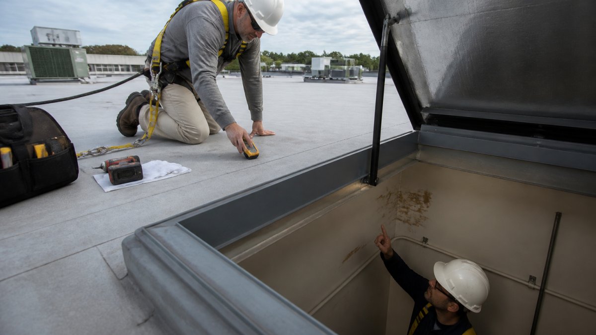 Roofing technician using a moisture meter to trace roof leaks that travel on a commercial flat roof membrane.