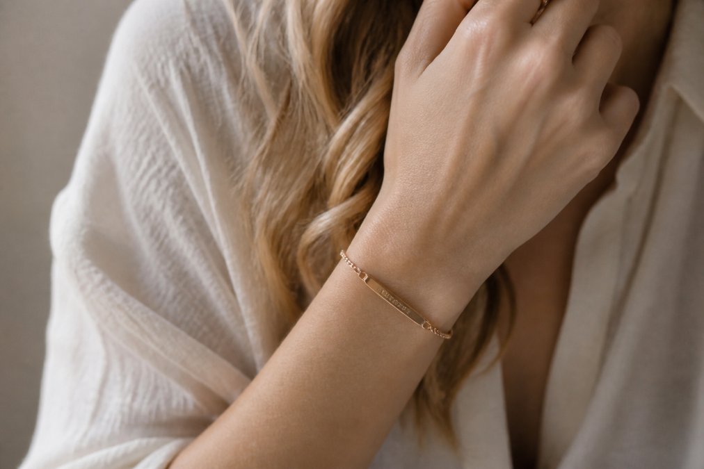 Close-up of a woman's hand wearing an engraved bracelet with soft warm lighting highlighting the personalized inscription and craftsmanship details