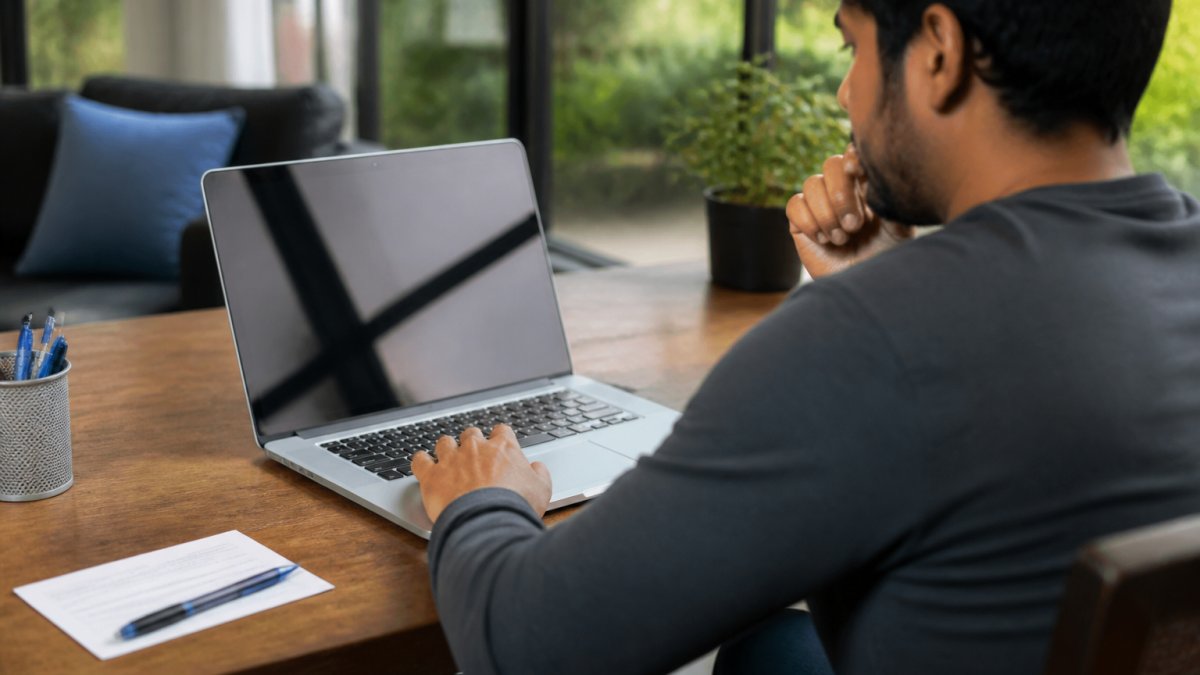 Person at a desk using a laptop to search for their congressional district with a voter registration card nearby
