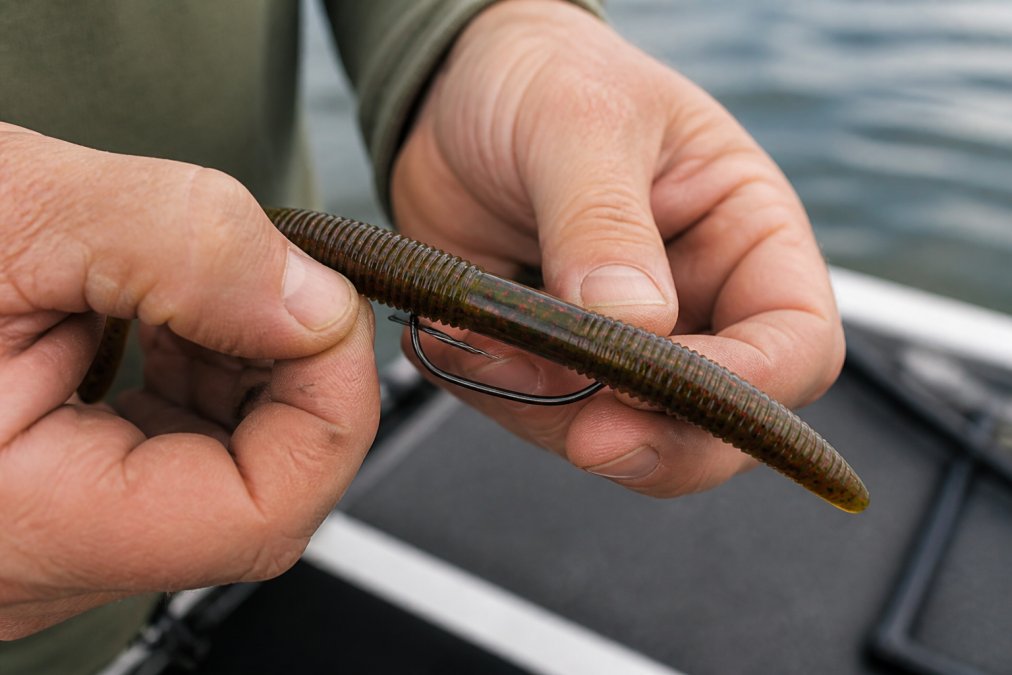 Diagram showing how to thread a soft plastic worm onto an offset hook for a weedless Texas rig setup.
