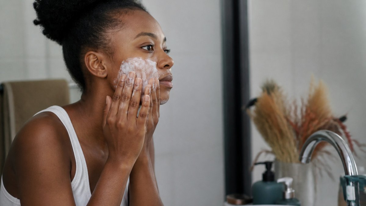 Person applying a thick cream to damp cheeks to soothe ashy dry skin