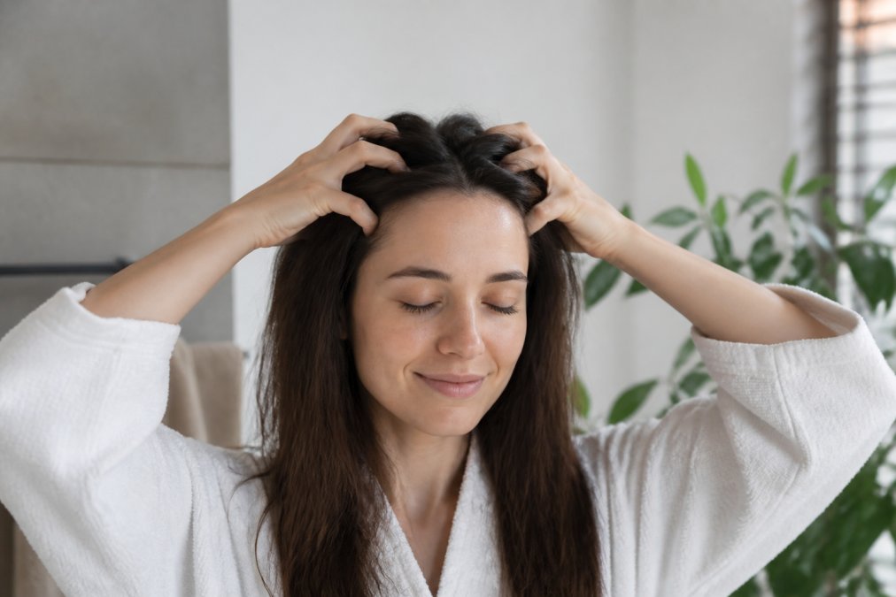Person performing gentle scalp massage with fingertips using proper technique, showing relaxed shoulders and calm expression in natural lighting