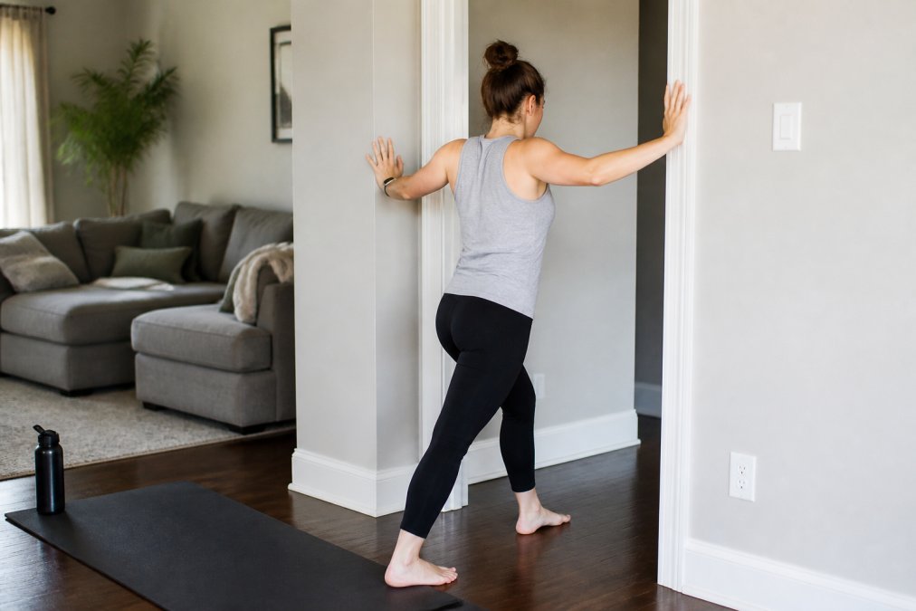 Person performing a doorway stretch in a bright living room to relieve upper back pain