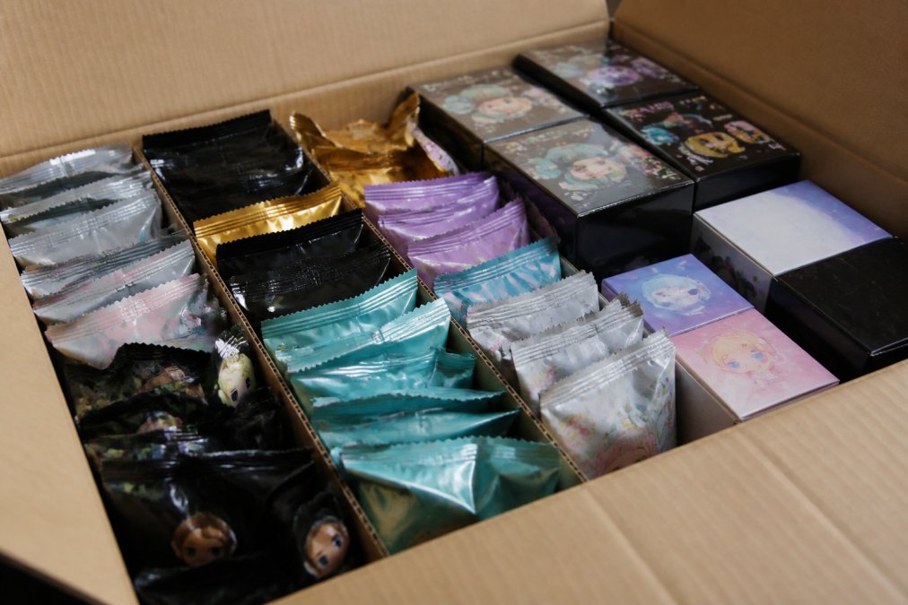 Close-up of an open blind box case showing multiple sealed packs arranged with visible packaging variations and different box designs stacked together