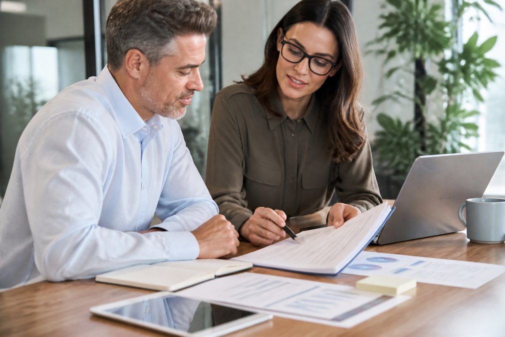 Financial advisor and business owner reviewing documents for commercial loan approval in a bright office