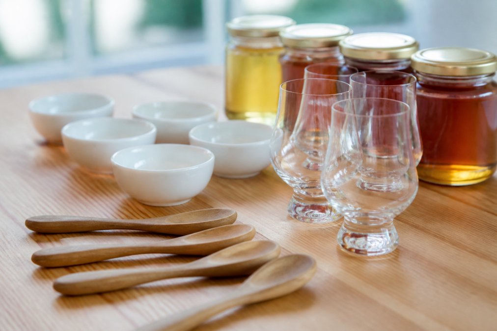 Layout of wooden spoons, ceramic bowls, and honey jars used for professional honey tasting sessions