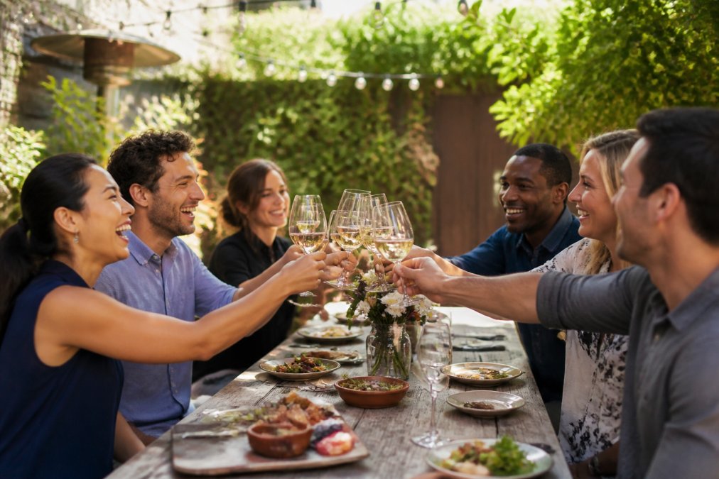 Infographic showing top-rated corporate team building venues in a sunlit garden patio setting with coworkers toasting.