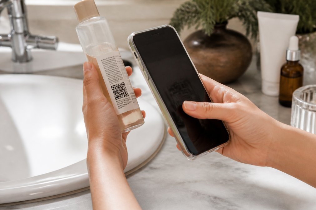 Hands scanning a QR code on a Korean skincare bottle to verify authenticity