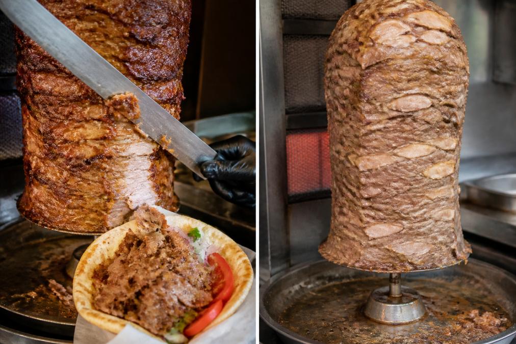 A close-up of a vertical rotisserie stacked with seasoned gyro meat, showing the crispy caramelized edges and juicy interior where a knife is slicing thin pieces onto a warm pita